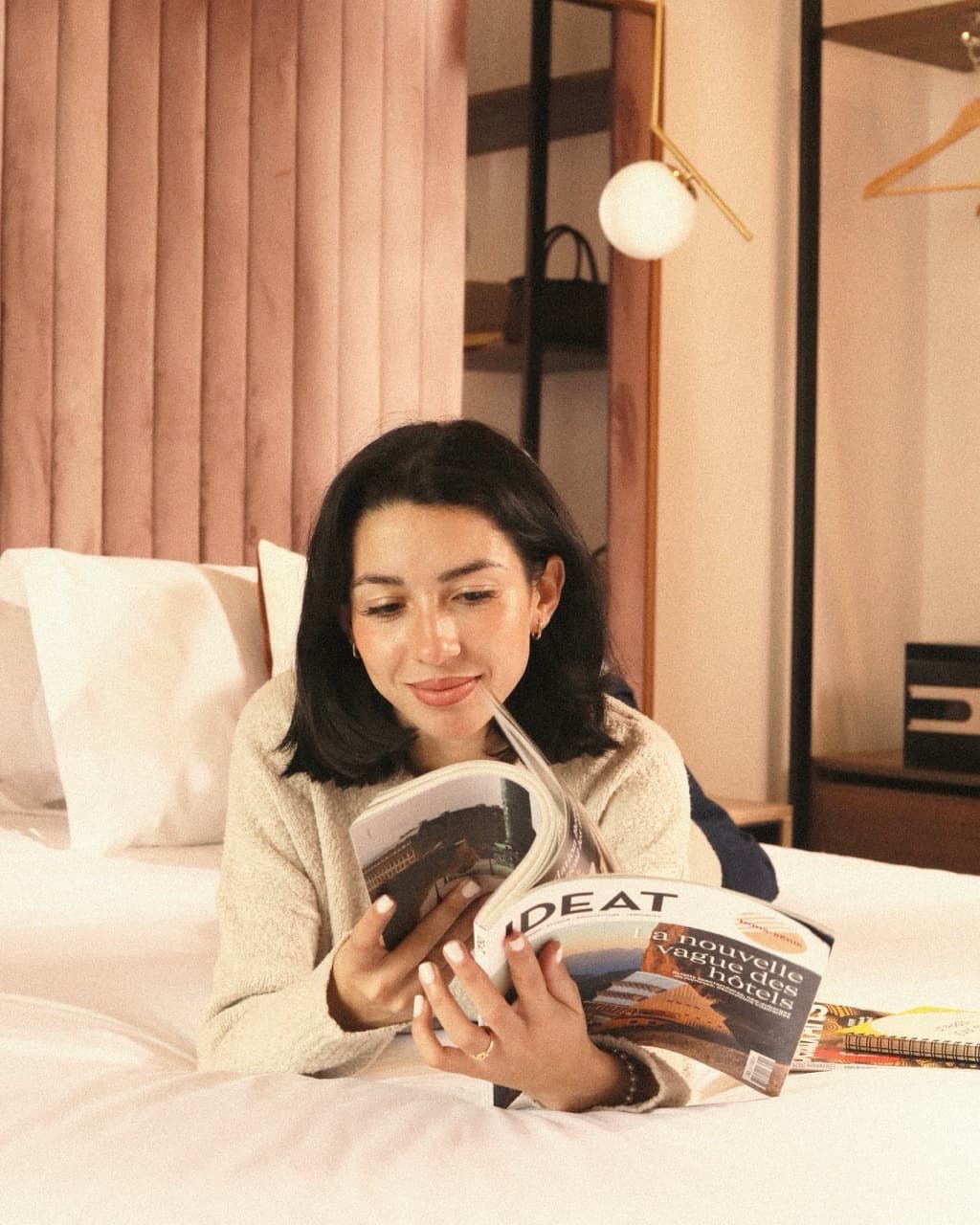 Traveler smiling while reading a magazine in bed